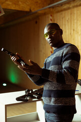 Portrait of shooting range client reloading handgun magazine, preparing to shoot targets, having...