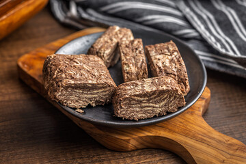Halva with cocoa. Sweet oriental dessert on plate on wooden table.