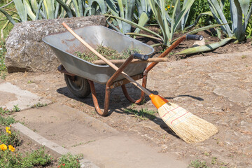 Garden Worksite Essentials: Wheelbarrow and Broom on Stone Path