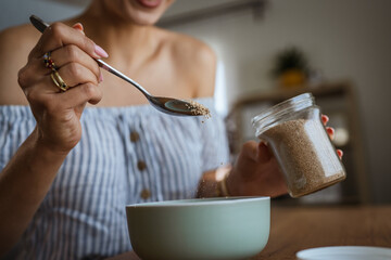 close up on female hands hold spoon with oat flakes and make breakfast