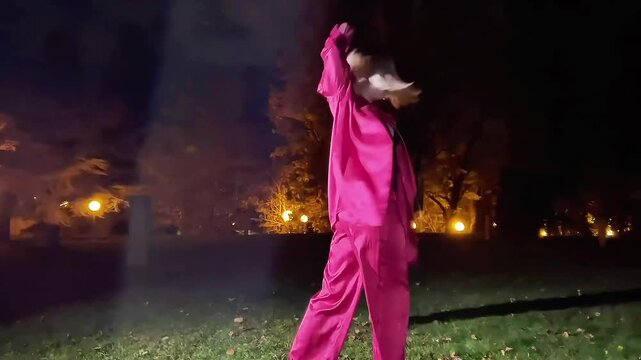 Young blonde woman dancing waacking in a park at night