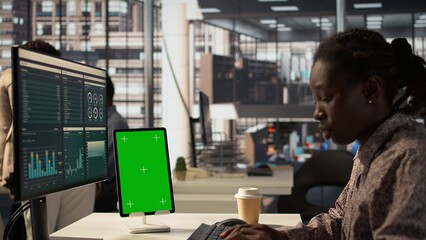 Fototapeta premium African American businessman at desk with mockup screen analyzing financial data and developing growth strategies to achieve enterprise success. Analyst managing important tasks. Camera B.