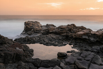 Volcanic tide pool reflecting a dramatic sunset. Travel Concept