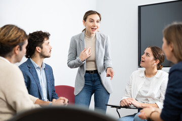 Young female professor explaining subject to classroom full of students