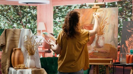 Female painter using watercolor paint and mixing colors on palette for her artistic creation in...
