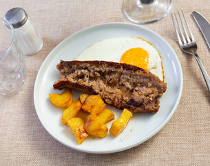 Appetizing dish of fried potatoes, cut into pieces, with fried eggs and baked sausage