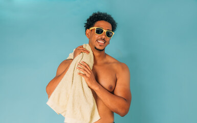 smiling young man wearing sunglasses in swim trunks isolated on white background with a beach or...