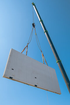 Prefabricated concrete wall being lifted by crane at construction site