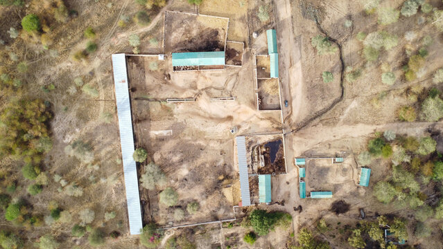 Aerial view of a rural farm complex with multiple buildings and enclosures in a dry landscape setting tanzania