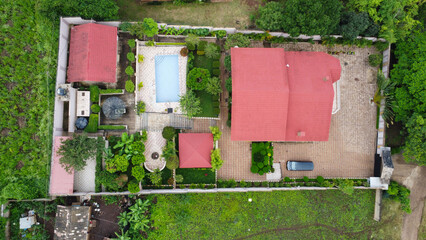 Aerial view of a large residential property with red roofs and a swimming pool surrounded by...
