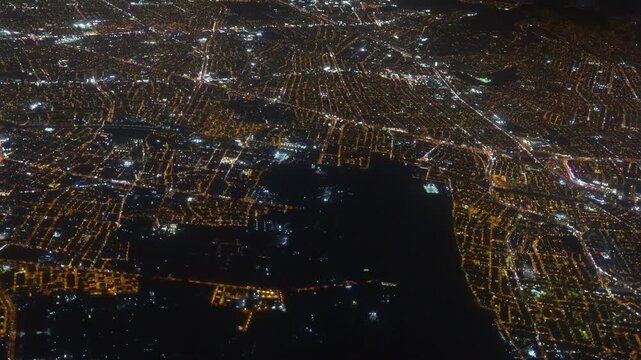 Night city view from airplane. Urban lights, illuminated streets, aerial perspective, skyline, buildings, travel, aviation, high altitude, cityscape, glowing grid. City of Lima from the aerial view