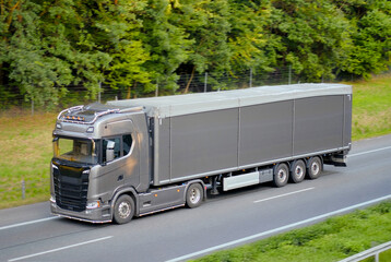 Modern Sustainable  Grey Semi Truck with Tarp-Covered Trailer on Forest Highway