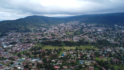 Aerial view of a densely populated town nestled in a valley surrounded by rolling green hills under a cloudy sky tanzania