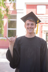 Caucasian young man in graduation gown communicating using sign language. 
