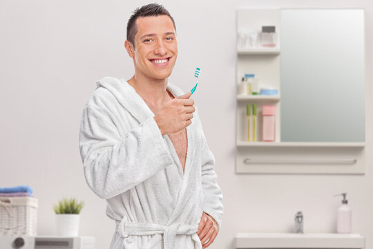 Man in a white bathrobe holding toothbrush