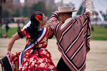 Portrait of a smiling young couple dressed as Chilean huasos, posing and joyfully dancing cueca...