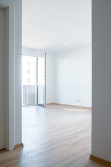 Bright empty apartment interior with wooden floor and open balcony door