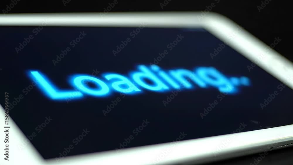 Poster blue loading text on a tablet screen with dark background and blurred edges