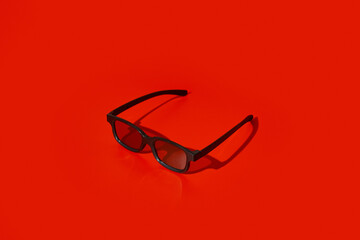 Black plastic 3d glasses on red background with copy space