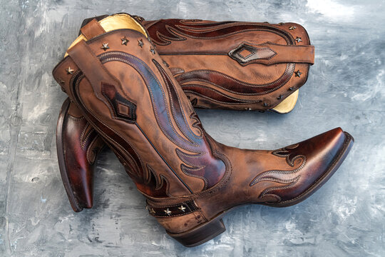 Cowboy boots made of cowhide leather with decorative trim.