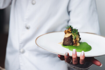 Waiter in uniform serving dishes on party event, server carrying plates with food at the table,...