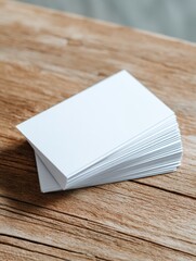 Fototapeta premium Stack of blank white paper business cards on wooden table surface.
