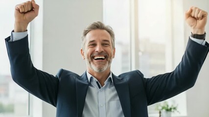 Mature businessman celebrating success in the office. Happy middle-aged professional man with arms raised in victory. Cheerful executive feeling triumphant.