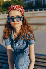 lifestyle woman in modern boho-western denim street style wearing oversized blue sunglasses and red...