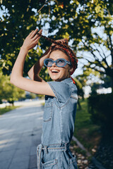 Lifestyle woman in modern boho-western denim street style wearing blue sunglasses joyfully plays...