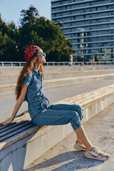lifestyle woman wearing modern boho-western denim outfit with street style sitting outdoors in...