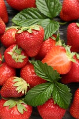 Fresh ripe strawberries and leaves on black wooden table, flat lay