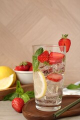 Tasty refreshing drink with strawberries, lemon and mint on wooden table, closeup