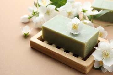 Soap bar and jasmine flowers on light brown background, closeup