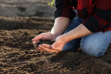 Man holding pile of soil in field, closeup