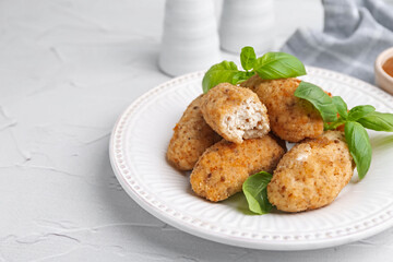 Tasty fried croquettes and basil on white textured table, closeup. Space for text