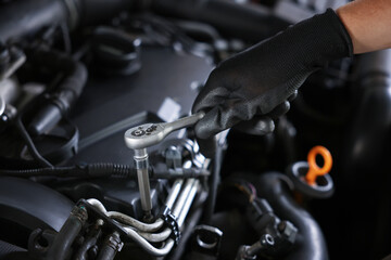 Auto parts. Professional mechanic with torque wrench fixing car indoors, closeup