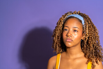 Young african american model posing with serious expression on purple background