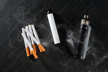 Electronic smoking devices and cigarettes on black table, flat lay