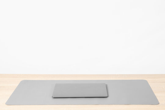 Stylish workplace with laptop and grey mousepad on wooden table indoors. Space for text
