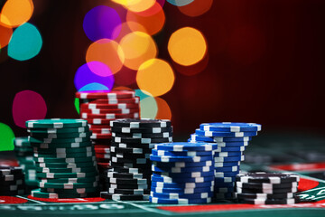 Casino chips on roulette table against blurred lights, closeup