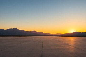 Serene sunset bathes distant mountains, its warm glow reflecting on expansive concrete surface.