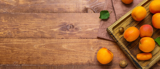 Board with fresh apricots on wooden table