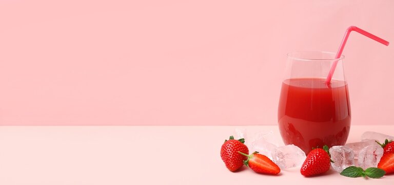 Glass of tasty strawberry juice and ice cubes on pink background with space for text