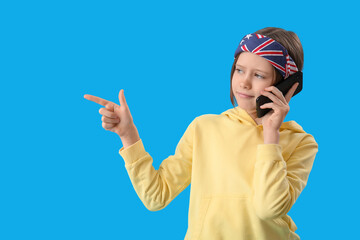 Little girl talking by mobile phone on blue background