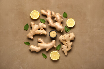 Fresh ginger roots with sliced lemon, leaves and bowl of dried powder on brown background