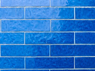 A close-up of a wall featuring various shades of blue rectangular tiles
