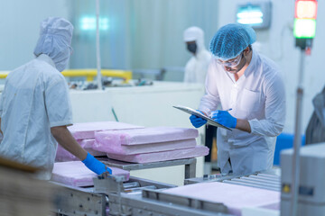 A quality control inspector in a food processing facility monitors production, ensuring hygiene, safety, and compliance with regulations in a modern industrial packaging line.