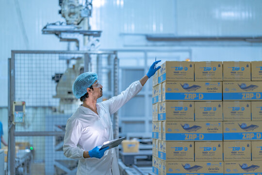 A logistics and supply chain professional performs inventory control and stocktaking in a modern warehouse using a digital tablet for efficiency.