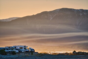 Stunning sunset view with mountains, flouting mist and motorhomes in Kaikoura, New Zealand