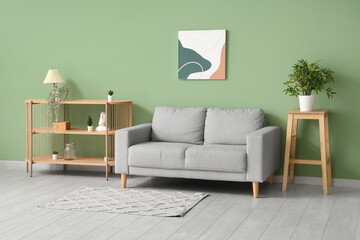 Stylish interior of living room with soft sofa and shelving unit near color wall